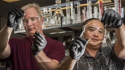 Sandia National Laboratories researchers Cy Fujimoto, right, and Michael Hibbs demonstrate the clarity of their recent membranes.