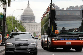 In this July 15, 2016, photo, a double decker tour bus drives by an Audi self driving vehicle parked on Pennsylvania Avenue, near the Capitol in Washington. The federal government should be in charge of regulating self-driving cars rather than states since the vehicles are essentially controlled by software, not people, Obama administration officials said Sept. 19 as they laid out the broad outlines of their plans to help get the transformational technology safely onto the nation’s roadways.