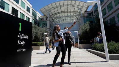 In this Aug. 31, 2016 photo, Alejandra Vicuna, of Miami, Fla., takes a selfie in front of the Apple campus in Cupertino, Calif. There's a quirky twist in tourism emerging amid the Silicon Valley whirlwind of innovation that has tethered everyone to their smartphones. Those omnipresent devices are now being used to track down technological touchstones so selfies can be taken, videos can be recorded and the experience can be celebrated in a Facebook post, Snapchat or tweet.