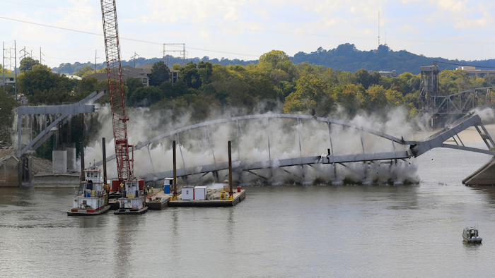 The steel arch of the Broadway Bridge falls into the Arkansas River after being pulled down by a pair of tug boats,