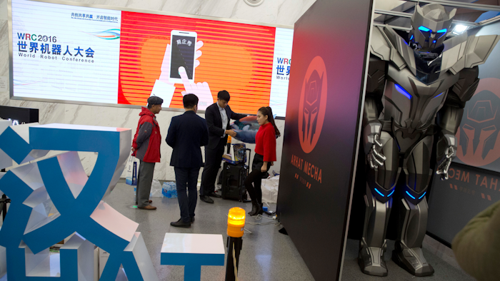 A group of visitors stand near a giant robot standing behind a partition at the World Robot Conference in Beijing.