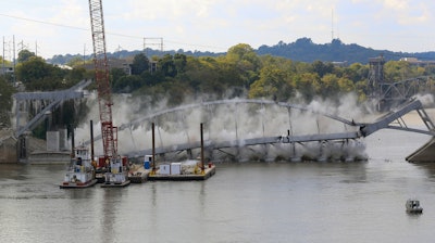 The steel arch of the Broadway Bridge falls into the Arkansas River after being pulled down by a pair of tug boats,
