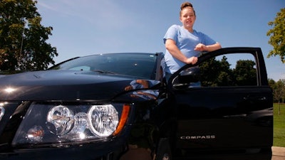 Alaina Dishman poses with her new Jeep Compass, in Delta Township, Mich., near Lansing. Dishman was among those who didn’t have enough credit to buy a new car when she went to a showroom last summer. But a salesman got her into a program that helps young people build credit.