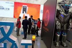 A group of visitors stand near a giant robot standing behind a partition at the World Robot Conference in Beijing.