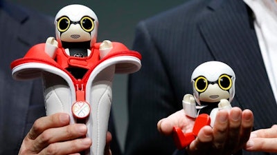 Toyota Motor Corp. SMO Moritaka Yoshida, right, and Fuminori Kataoka, project general manager from Toyota Motor Corp., pose for photographers with compact sized humanoid communication robots, Kirobo Mini, during a press unveiling in Tokyo. The new robot from Japanese automaker Toyota Motor Corp. can’t do much else but chatter in a high-pitched voice.