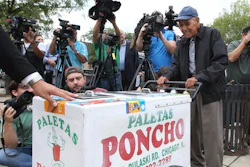 In this photo taken Sept. 21, 2016, a grateful Fidencio Sanchez pushes his paletas cart one last time before a group of of media after accepting a check for $384,290 during a news conference outside the ice cream shop, Paleteria y Neveria Poncho, where he rented his paletas cart in Chicago's Little Village.