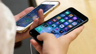 In this Sept. 16, 2016, file photo, Lisa Gao, from Chicago, compares a new jet black iPhone 7, right, with her iPhone 6 at an Apple Store in Chicago. Apple said in a lawsuit filed Monday, Oct. 17, 2016, that it has been buying Apple products labeled as genuine on Amazon.com and has found nearly 90 percent of them are counterfeit.