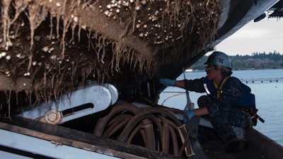 A Sailor scrapes barnacles from the bottom of a rigid-hull inflatable boat aboard the aircraft carrier USS John C. Stennis (CVN 74). When clustered in thick clumps on a vessel's hull, barnacles can slow the ship and increase its fuel consumption. The Office of Naval Research is sponsoring research to develop environmentally friendly hull coatings to fight off barnacles.