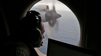 In this March 22, 2014 file photo, flight officer Rayan Gharazeddine scans the water in the southern Indian Ocean off Australia from a Royal Australian Air Force AP-3C Orion during a search for the missing Malaysia Airlines Flight MH370. A ship involved with the deep-sea sonar search for missing Malaysia Airlines Flight 370 is being fitted with equipment to examine several sonar contacts of interest on the remote seabed west of Australia, the Australian Transport Safety Bureau said on Wednesday, Oct. 19, 2016.
