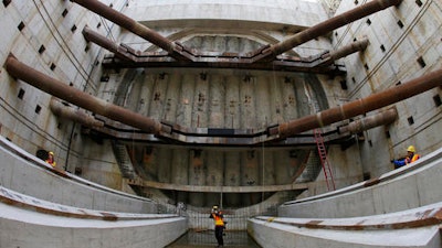 In this photo made with a fish-eye lens, reporters and photographers stand in the pit where a tunnel boring machine known as 'Bertha' will emerge when the nearly 2-mile tunnel of the Highway 99 project to replace the earthquake-damaged Alaskan Way Viaduct is completed during a media tour, Monday, Oct. 3, 2016, in Seattle. Officials said Monday that the machine had passed the halfway mark as it digs beneath the city.