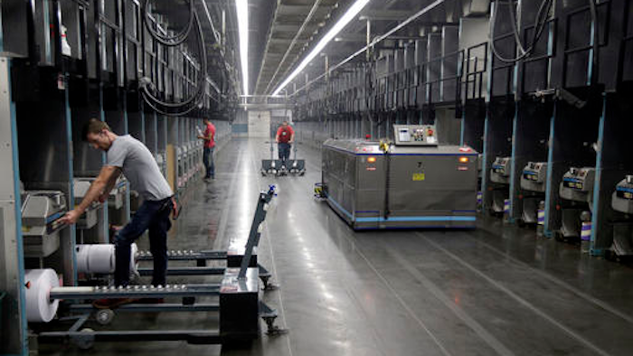 Workers exchange spools of thread as a robot picks up thread made from recycled plastic bottles at the Repreve Bottle Processing Center, part of the Unifi textile company in Yadkinville, N.C., Friday, Oct. 21, 2016. America has lost more than 7 million factory jobs since manufacturing employment peaked in 1979. Yet American factory production, minus raw materials and some other costs, more than doubled over the same span to $1.91 trillion last year, according to the Commerce Department, which uses 2009 dollars to adjust for inflation. That’s a notch below the record set on the eve of the Great Recession in 2007. And it makes U.S. manufacturers No. 2 in the world behind China.