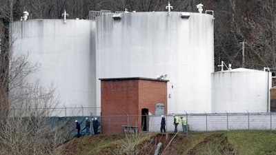 In this Monday, Jan. 13, 2014, file photo, workers inspect an area outside a retaining wall around storage tanks where a chemical leaked into the Elk River at Freedom Industries storage facility in Charleston, W.Va. A federal judge is expected to hear details, Monday, Oct. 31, 2016, of a potential tentative settlement between a water company and plaintiffs who sued over the company's handling of a 2014 chemical leak in southern West Virginia.