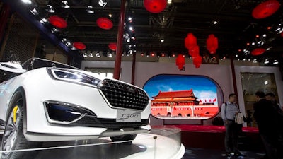 In this April 25, 2016 file photo, visitors to Auto China 2016 stand near Zotye Auto's T300 SUV displayed in Beijing, China. China's auto sales rose 20.3 percent in October from a year earlier, propelled by surging demand for sport utility vehicles, an industry group reported Thursday, Nov. 10, 2016.