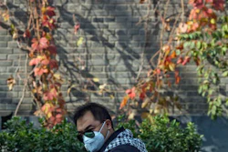 A man wears a mask during a heavily polluted day in Beijing, China, Saturday, Nov. 5, 2016. China has announced a plan to curb greenhouse gas emissions over the next several years, while capping coal consumption and increasing the use of non-fossil fuels. Under the plan, by 2020, the level of carbon dioxide emissions per unit of GDP will be 18 percent lower than in 2015, the State Council said on its website Friday, Nov. 4.