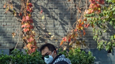 A man wears a mask during a heavily polluted day in Beijing, China, Saturday, Nov. 5, 2016. China has announced a plan to curb greenhouse gas emissions over the next several years, while capping coal consumption and increasing the use of non-fossil fuels. Under the plan, by 2020, the level of carbon dioxide emissions per unit of GDP will be 18 percent lower than in 2015, the State Council said on its website Friday, Nov. 4.