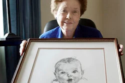 In this Feb. 4, 2004, file photo, Ann Taylor Cook, poses at her Tampa, Fla., home with a copy of her photo that is used on all Gerber baby food products. Gerber says Cook turned 90 on Sunday, Nov. 20, 2016.