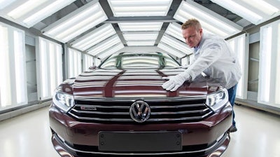 In this file photo, worker Maik Neubert checks a Passat Variant car during the visual inspection during a press tour at the plant of the German manufacturer Volkswagen Sachsen in Zwickau, Germany. Volkswagen has announced significant job cuts as it looks to recover from the emissions-rigging scandal first brought to light in 2015.