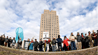 Dakota Pipeline protesters stand arm-in-arm in front of the state Capitol in Bismarck, N.D., before marching downtown to the William L. Guy Federal Building.
