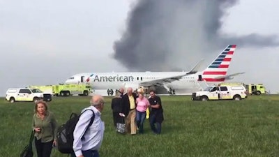 In this photo provided by passenger Jose Castillo, taken Oct. 28, 2016, fellow passengers walk away from a burning American Airlines jet that aborted takeoff and caught fire on the runway at Chicago's O'Hare International Airport. An engine disk that broke apart and forced an American Airlines jet to abort a takeoff in Chicago last week shows signs of fatigue cracking, according to a preliminary report released Friday, Nov. 4, 2016, by accident investigators.