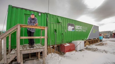 In this Oct. 26, 2016 photo provided by Will Anderson, employee Joe Carr stands outside a new indoor hydroponics farm owned by a local Alaska Native corporation in Kotzebue, Alaska. Arctic Greens is harvesting kale, various lettuces, basil and other greens weekly from the soil-free system and selling them at the supermarket in the community of nearly 3,300.