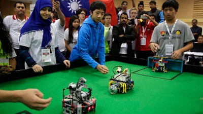 In this Sunday, Nov. 27, 2016, photo, participants from Taiwan watch their robots playing a soccer match during the World Robot Olympiad in New Delhi, India. The weekend games brought more than 450 teams of students from 50 countries to the Indian capital.