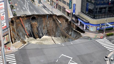 A massive sinkhole is created in the middle of the business district in Fukuoka, southern Japan Tuesday, Nov. 8, 2016. Parts of a main street have collapsed in the city, creating a huge sinkhole and cutting off power, water and gas supplies to parts of the city. Authorities said no injuries were reported from Tuesday's pre-sunrise collapse in downtown Fukuoka.