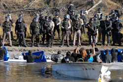 Dakota Access Pipeline protesters stand waist deep in the Cantapeta Creek, northeast of the Oceti Sakowin Camp, near Cannon Ball, N.D., Wednesday, Nov. 2, 2016. Officers in riot gear clashed again Wednesday with protesters near the Dakota Access pipeline, hitting dozens with pepper spray as they waded through waist-deep water in an attempt to reach property owned by the pipeline's developer.
