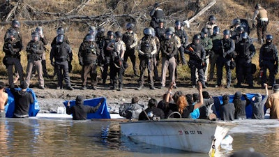 Dakota Access Pipeline protesters stand waist deep in the Cantapeta Creek, northeast of the Oceti Sakowin Camp, near Cannon Ball, N.D., Wednesday, Nov. 2, 2016. Officers in riot gear clashed again Wednesday with protesters near the Dakota Access pipeline, hitting dozens with pepper spray as they waded through waist-deep water in an attempt to reach property owned by the pipeline's developer.