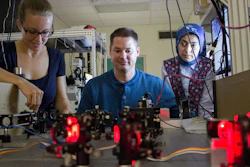 UNM Associate Professor Keith Lidke (center) is working at an optics table with post-doctoral student Marjolein Meddens (l.) and graduate student Hanieh Mazloom-Farsibaf (r.).