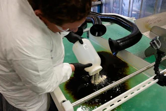 PNNL microbiologist Robert Jeters sprinkles PNNL's chemically modified sawdust onto a small oil spill inside the Arctic simulation lab, where researchers mimic extreme freezing conditions and make icy slush that is similar to what is found on the surface of the Arctic Sea.
