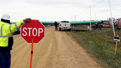 In this file photo, a crew member stops traffic as work resumed on the four-state Dakota Access pipeline near St. Anthony, N.D. Energy Transfer Partners, the company building the pipeline, is fighting an effort by North Dakota regulators to fine it $15,000.