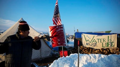 Benji Buffalo, a Grovan Native American from Montana, shovels snow outside his tent at the Oceti Sakowin camp where people have gathered to protest the Dakota Access oil pipeline in Cannon Ball, N.D., Saturday, Dec. 3, 2016.