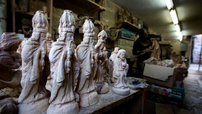 In this Monday, Dec. 12, 2016 photo, Palestinian woodcarver Muhammad Yusuf, works on olive wood figures in the West Bank city of Bethlehem. Christmas is approaching and pilgrims and tourists have begun to arrive, crowding the souvenir shops that line the narrow streets and allies of the city where Jesus is said to have been born. But when visitors choose to take a piece of the Holy Land back home with them, they better check the labels. Many souvenirs, including the West Bank town’s trademark rosemary beads, are imported from abroad, mainly China.