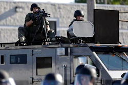 In this Aug. 9, 2014, file photo, a police tactical team moves in to disperse a group of protesters following the shooting of a young black man by a white policeman in Ferguson, Mo. If president-elect Donald Trump keeps his promise, surplus military grenade launchers, bayonets, tracked armored vehicles and high-powered firearms and ammunition will once again be available to state and local U.S. police departments. National police organizations say they'll hold Trump to that promise.