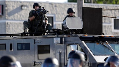 In this Aug. 9, 2014, file photo, a police tactical team moves in to disperse a group of protesters following the shooting of a young black man by a white policeman in Ferguson, Mo. If president-elect Donald Trump keeps his promise, surplus military grenade launchers, bayonets, tracked armored vehicles and high-powered firearms and ammunition will once again be available to state and local U.S. police departments. National police organizations say they'll hold Trump to that promise.