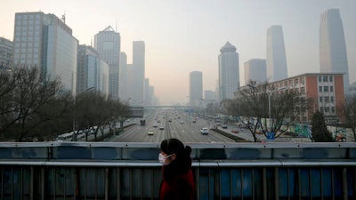 A woman wearing a mask for protection against air pollution walks on a pedestrian overhead bridge in Beijing as the capital of China is shrouded by heavy smog Monday, Dec. 19, 2016. Engulfed in choking smog, some northern Chinese cities limited the number of cars on roads and temporarily shut down factories on Monday to cut down pollution during a national 'red alert.' More than 700 companies stopped production in Beijing and traffic police were restricting drivers by monitoring their license plate numbers, state media reported.