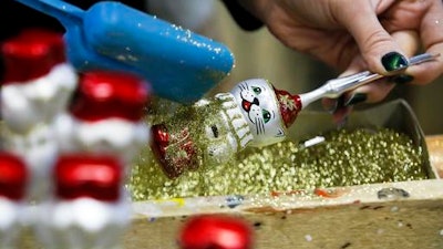 In this photo taken on Thursday, Nov. 24, 2016, a worker adorns Christmas decorations in the Christmas decorations museum in Klin, about 85 kilometers (53 miles) northwest of Moscow.