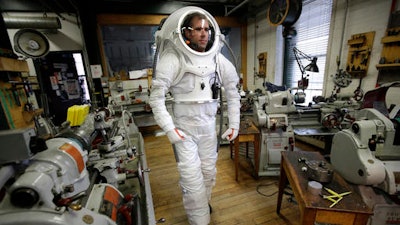 In this Monday, Dec. 5, 2016 photo, Andrzej Stewart, the chief engineering officer on a year-long Mars simulation mission that ended in August, walks through a machine shop at the Rhode Island School of Design (RISD), while wearing a new space suit that the school created in Providence, R.I. RISD staff and students have come up with the new suit that closely resembles an actual space suit. Real space suits are designed to work in zero gravity. They're too expensive and too heavy to use at the NASA-funded Mars simulation mission in Hawaii.