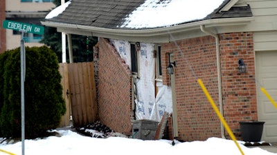 In this Saturday, Dec. 24, 2016 photo, bricks are falling off the exterior wall of a house sitting over a sinkhole, in Fraser, Mich. The major sinkhole disrupted the holiday season in Fraser, a Detroit suburb of roughly 14,500 people about 15 miles north of downtown and five miles west of the Great Lakes waterway of Lake St. Clair.