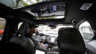 In this Tuesday, Dec. 13, 2016, file photo, Devin Greene sits in the front seat of an Uber driverless car during a test drive in San Francisco.
