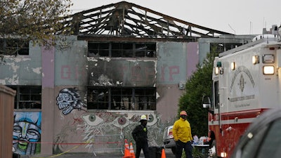 A pair of Oakland fire officials walk past the remains of the Ghost Ship warehouse fire Wednesday, Dec. 7, 2016, in Oakland, Calif. The fire that killed 36 people during a party at an Oakland warehouse started on the ground floor and quickly raged, with smoke billowing into the second level and trapping victims whose only escape route was through the flames, federal investigators said Wednesday.