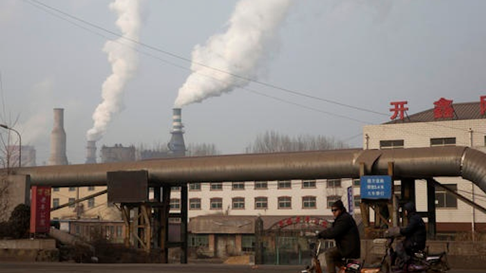 A man rides a bike past smoke spewing from the sprawling complex that is a part of the Jiujiang steel and rolling mills in Qianan in northern China's Hebei province. China's top economic planner pledged Tuesday, Jan 10, 2017, to continue cutting steel and coal production that have been a source of trade friction with many countries.