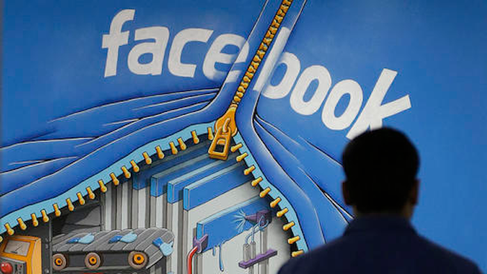 In this Friday, March 15, 2013, file photo, a Facebook employee walks past a sign at Facebook headquarters in Menlo Park, Calif. Despite loudly touted efforts, the tech industry is making very little progress in diversifying its workforce, especially in technical and leadership positions. In 2014, 2 percent of Googlers were black and 3 percent were Hispanic, numbers that haven’t changed since. The picture is similar at Facebook and Twitter.