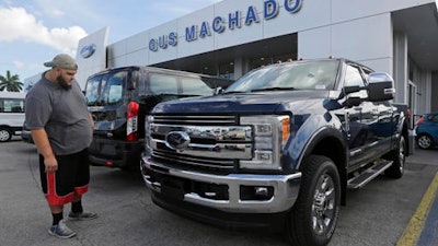 In this Tuesday, Jan. 17, 2017, photo, a potential customer looks at a 2017 Ford F-250 Lariat FX4 at a Ford dealership, in Hialeah, Fla. Ford Motor Company reports financial results Thursday, Jan. 26, 2017.