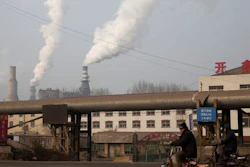 A man rides a bike past smoke spewing from the sprawling complex that is a part of the Jiujiang steel and rolling mills in Qianan in northern China's Hebei province. China's top economic planner pledged Tuesday, Jan 10, 2017, to continue cutting steel and coal production that have been a source of trade friction with many countries.