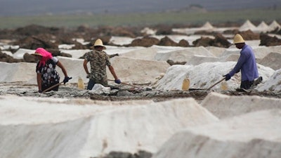 In this Aug. 13, 2011 photo, migrant workers shovel raw salt at the Qijiaojing Salt Field in Hami in northwest China's Xinjiang Uygur Autonomous Region. China has started an overhaul of its salt industry, easing a monopoly that has existed in some form for more than 2,000 years and predates the Great Wall.