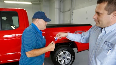 FILE - In this Thursday, Nov. 19, 2015, file photo, Alton John, left, from Kittanning, Pa., gets the keys to his new 2015 Ford F-150 Supercab 4x4 pickup truck from salesman Robert Myers as he takes delivery at Butler County Ford in Butler, Pa. U.S. car shoppers will find plentiful deals, relatively low interest rates and lots of high-tech choices in the market in 2017.