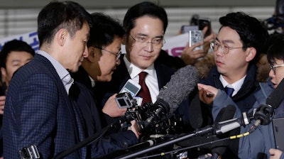 In this Jan. 12, 2017 photo, Lee Jae-yong, center, vice chairman of Samsung Electronics, arrives to be questioned as a suspect in bribery case in the massive influence-peddling scandal that led to the president's impeachment at the office of the independent counsel in Seoul, South Korea.