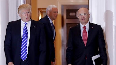 In this Nov. 19, 2016 file photo, President-elect Donald Trump walks Labor Secretary-designate Andy Puzder from Trump National Golf Club Bedminster clubhouse in Bedminster, N.J. Puzder was CEO of a fast food empire that is outsourcing jobs on his watch, a stark contrast with his boss' threats and tweeted slaps at companies that outsource jobs.