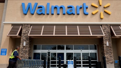 In this file photo, a worker pushes shopping carts in front of a Wal-Mart store in La Habra, CA.